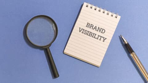 Brand visibility concept with magnifying glass and pen on notebook