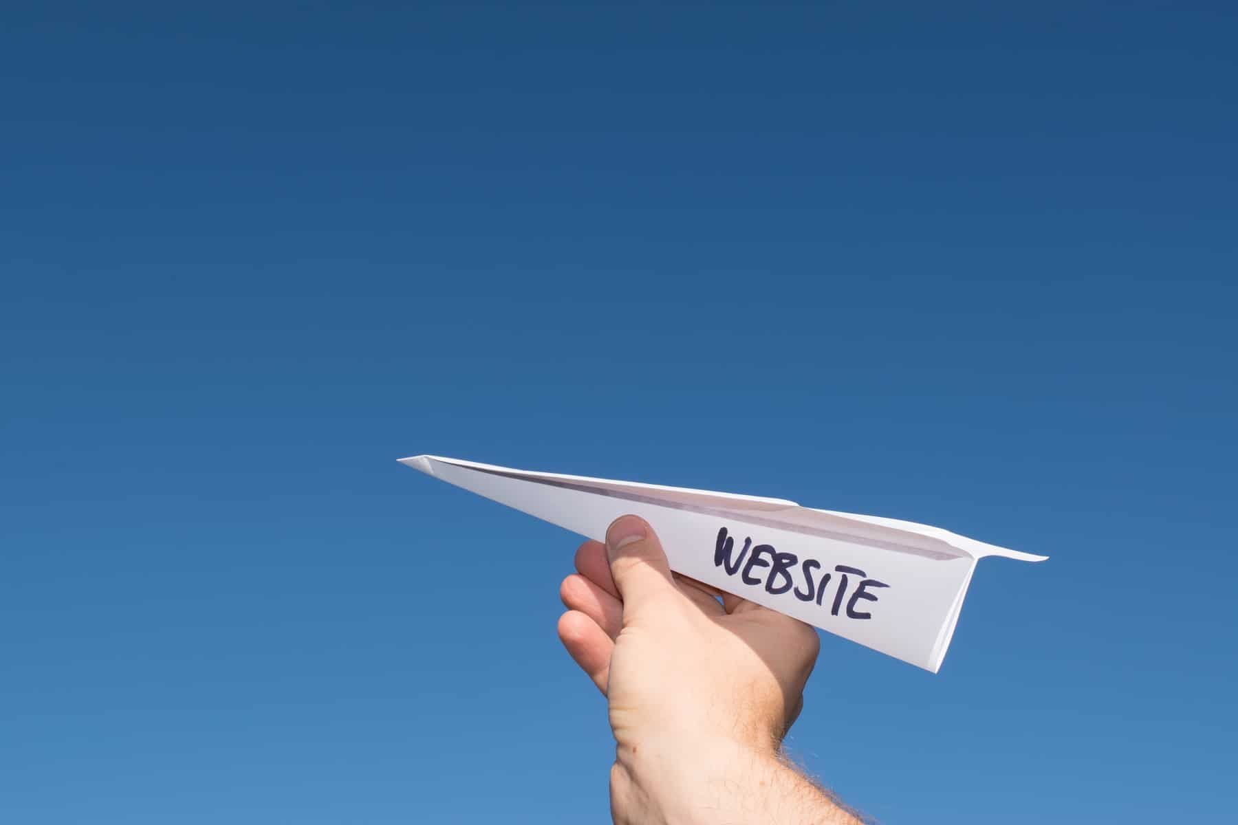paper airplane with the word "website" - launch a new website redesign